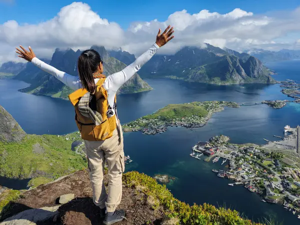 stock image A traveler stands atop a mountain, arms outstretched in joy, overlooking the stunning Lofoten Islands and vibrant fjords. Reinebringen Lofoten Norway 