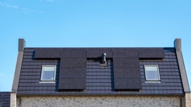 Güneş panelleri modern bir çatıya yerleştirilmiş güneş ışığını yakalıyor ve sakin bir ortamda sürdürülebilir enerji kullanımı sergiliyor. Zonnepanelen, Zonne Energie, Çeviri: Güneş Paneli, Güneş Enerjisi