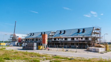 30 Temmuz 2024 'te Urk Hollanda' da, canlı bir Hollanda banliyösünde, parlak bir gökyüzüne karşı modern mimari sergilenen yeni inşa edilmiş aile evleri ortaya çıktı..