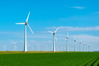 Uzun rüzgar türbinleri, canlı mavi gökyüzüne karşı zarafetle dönüyor. Hollanda 'daki araziye enerji sağlamak için rüzgar enerjisini kullanıyorlar..