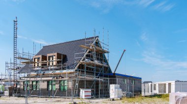 Parlak gökyüzüne karşı inşaat ilerlemesi. Modern aile evleri olan yeni bir Hollanda Suburban bölgesinin inşaatı, Hollanda 'da yeni inşa edilen modern aile evleri 