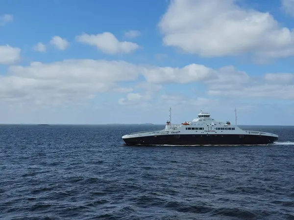 stock image Stavanger Norway 12 June 2024, A ferry gracefully glides across the serene waters of Norway, glinting under the bright sun, against a backdrop of fluffy clouds.