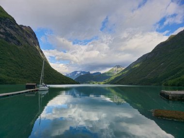 Sakin sular, Urke Norveç 'te sakin bir rıhtımda demirleyen bir yelkenli gibi yükselen tepeleri ve bereketli manzaraları yansıtıyor..