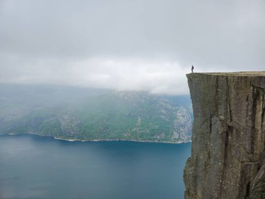 Yalnız bir figür Preikestolen 'in kenarında duruyor, sisli dağlarla çevrili nefes kesici Lysefjord' a bakıyor. Önceki Norveç