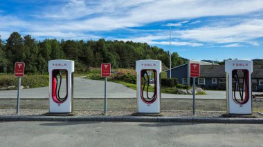 Odda Norveç 25 Haziran 2024, Tesla Superchargers açık bir gökyüzünün altında dizilmiş, Norveç 'in sakin manzarasının ortasındaki elektrikli araçlara güç sağlıyor..