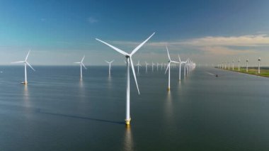 Bu hava görüntüsünde Hollanda 'nın sakin sularında sürdürülebilir bir gelecek için gerekli olan yenilenebilir enerjinin güzelliği ve verimliliğini vurgulayan yel değirmeni türbinleri görülüyor.