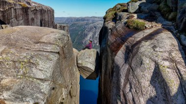 Dengesiz bir kayanın üzerinde, nefes kesen fiyortlarla çevrili yüksek uçurumlar arasında tehlikeli bir şekilde sendeleyen cüretkar bireysel bir tünek. Kjerag Kjeragbolten Lysefjord Norveç