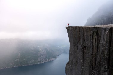 Sisli ortamların ortasında, iki maceracı Preikestolen Cliff 'in kenarında duruyor, aşağıdaki büyüleyici Lysefjord' a bakıyor, doğanın ihtişamı ve sükunetini kucaklıyor. Önceki Norveç