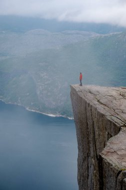 Norveç 'in fiyortlarının ruhani sisi ve dingin sularıyla çevrili, nefes kesici uçurumlara canlı giysiler içinde tek başına bakan bir figür. Önceki Norveç
