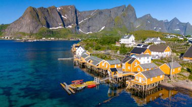 Huzurlu bir körfez boyunca uzanan sazların üzerinde canlı sarı evler ve dik dağlar Norveç 'in cennet manzarasını çerçeveliyor. Sakrisoy, Norveç