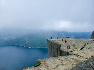  Jorpeland Norveç 14 Haziran 2024, Maceracılar Preikestolen 'in dramatik uçurumunda toplandılar, Lysefjord' un sisli manzaralarına hayret ederek şafak vakti gökyüzünü boyarken.