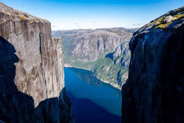 Sakin bir fiyordun yanında nefes kesici uçurumlar yükselir, canlı gökyüzünü ve yemyeşil suları yansıtır. Kjeragbolten Kjerag Lysefjorden Norveç