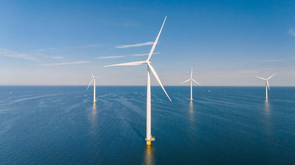 Высокие ветряные турбины стоят величественно над спокойными водами, превращая ветер в устойчивую энергию посреди спокойного голландского ландшафта.