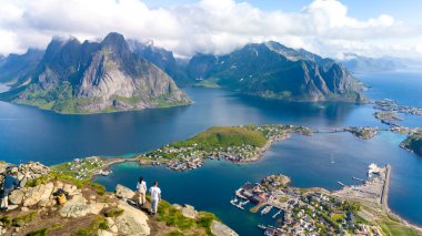 İki arkadaş kayalık bir çıkıntının tepesinde durmuş, dağların resim gibi bir gökyüzü altında kristal berrak sularla buluştuğu çarpıcı Lofoten Adaları 'na bakıyorlar. Reinebringen Lofoten Norveç