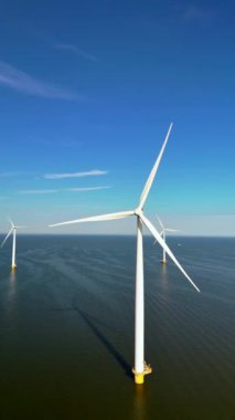 Bu hava fotoğrafı Hollanda 'daki rüzgar türbinlerinin panoramik bir görünümünü gösteriyor, sürdürülebilir enerji üretimine ve yenilikçi yenilenebilir uygulamalara olan bağlılıkları vurguluyor