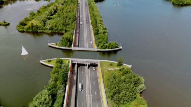 Hollanda 'daki Aqueduct Veluwemeer, verimli yeşilliklerle çevrili, zarafetle manzaralı bir su yolundan geçen güzel bir otoyol manzarası sunuyor. Doğayla mühendislik harikasının bir karışımı.
