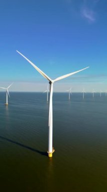 Bu hava manzarası, daha parlak bir gelecek için yeşil enerjinin ve sürdürülebilirliğin artan önemini sembolize eden Hollanda 'nın ikonik yel değirmenleri ve modern türbinlerini gösteriyor.