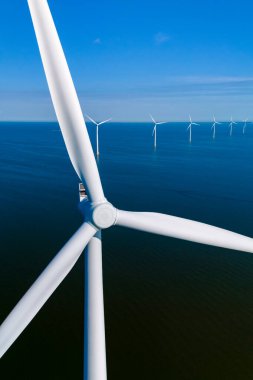 Parlak suların üzerinde zarif bir şekilde dönen parlak rüzgar türbinleri Hollanda kıyı şeridi boyunca sürdürülebilir enerji üretir..