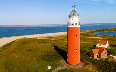 Texel Hollanda, Majestic deniz feneri sahile vuran dalgalarla kumsalda yükseliyor, geçen gemilere rehberlik ve güvenlik sağlıyor..
