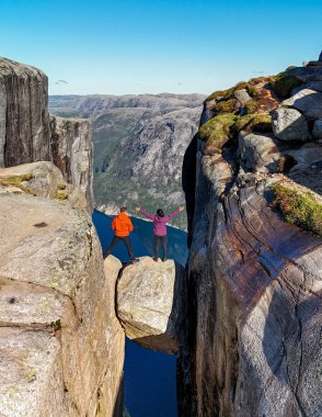 İki yürüyüşçü, göz kamaştırıcı Norveç manzaraları ve derin mavi su yollarıyla çevrili Preikestolen tepesindeki nefes kesici manzarayı kucaklıyor. Kjerag Kjeragbolten Lysefjord Norveç