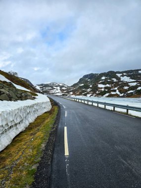Dolambaçlı bir yol, eriyen karları ve engebeli tepeleri geçerek Norveç 'in büyüleyici ilkbahar güzelliklerini gözler önüne seriyor..