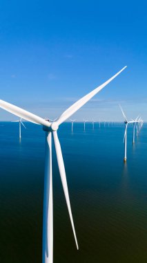 Yenilenebilir enerjiyi kullanan rüzgar türbinleri sakin suların üzerinde yavaşça dönerek Hollanda 'nın şafakta sürdürülebilirliğe olan bağlılığını gösteriyor..
