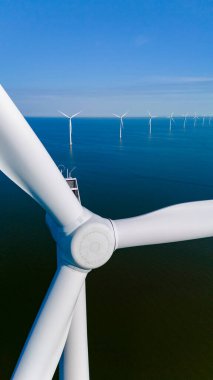 Uzun rüzgar türbinleri zarif bir şekilde dönüyor, Hollanda 'nın sakin suları üzerinde güçlü rüzgarlar esiyor, sürdürülebilir enerjiyi teşvik ediyorlar..