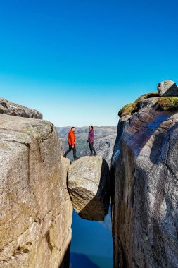 İki dağcı Norveç 'te sersemletici bir kayanın üzerinde duruyor, canlı mavi gökyüzüne karşı maceracı ruhlarını sergiliyorlar. Kjerag Kjeragbolten Lysefjord Norveç