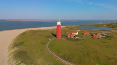 Hollanda 'nın güzel plajı boyunca yer alan ve canlı doğasını ve nefes kesici kıyı manzarasını gözler önüne seren ikonik Teksaslı Deniz fenerinin çarpıcı hava manzarasını deneyimleyin.