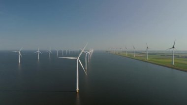 Hollanda, Flevoland 'daki çarpıcı yel değirmeni türbinlerini araştırın. Bu yapılar, gezegenimizin yararına ve iklim değişikliğine karşı verilen mücadeleye yardımcı olarak sürdürülebilir enerjiye hayati bir kaymayı temsil ediyor.