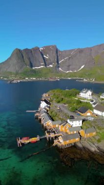 Norveç, Lofoten 'de Reine' in güzelliğini gösteren nefes kesici bir hava çekimi. Kristal berrak su, manzaralı dağlar ve büyüleyici balıkçı kulübeleri, Sakrisoy balıkçı köyü.