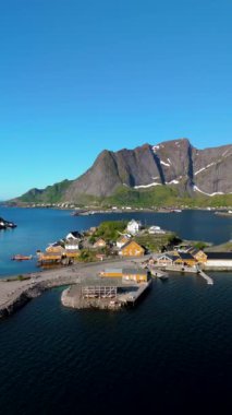 Lofoten Adaları 'ndaki Reine köyünün çarpıcı hava manzarasını deneyimleyin. Canlı renklerin görkemli dağlarla ve manzarayı yansıtan sakin sularla tezat oluşturduğu yer.