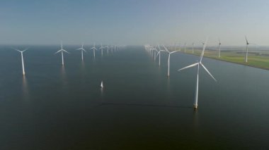 Hollanda, Flevoland 'ın hava manzarası, etkileyici yel değirmeni türbinleriyle daha sürdürülebilir ve yenilenebilir enerji geleceğine geçişi sembolize eden çarpıcı manzaralar sergiliyor.