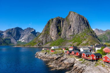 Norveç Lofoten Adaları 'nın göz kamaştırıcı güzelliğini tecrübe edin. Canlı kırmızı kulübeler, yüksek dağlar ve kristal berrak suların büyüleyici manzarayı yansıttığı Hamnoy balıkçı köyü. 