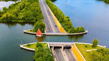 Veluwemeer Aqueduct Hollanda 'nın otoban üzerindeki bir kanaldan geçen yelkenlileri var. Göz kamaştırıcı bir hava manzarası var. Çevresi yeşilliklerle çevrili, görkemli su yollarıyla kesişen yollar..
