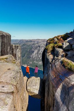İki kaşif dramatik bir uçurumun kenarında duruyor, Norveç 'te nefes kesici bir fiyorttan bakıyor, doğanın hayranlık uyandıran güzelliği tarafından kucaklanıyor. Kjerag Kjeragbolten Lysefjord Norveç