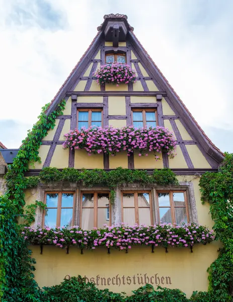 stock image Rothenburg ob der Tauber, 25 August 2024, the delightful half timbered house is covered in vibrant flowers, showcasing the beauty of traditional German architecture and enchanting street life.