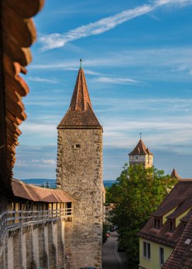 Almanya 'nın Rothenburg ob der Tauber şehrinde büyüleyici kuleler yükseliyor. Taştan yapılar ve çatılar yemyeşil ile harmanlanarak şehrin ortaçağ cazibesini alacakaranlıkta sergiliyor..