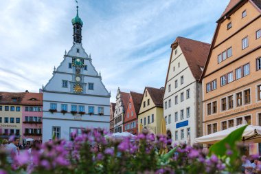 Rothenburg ob der Tauber 'deki ilginç bir meydanın etrafını saran renkli binaların cazibesine canlı çiçekler ekleniyor. Sahne, parlak ve güneşli bir günde bu tarihi kasabanın özünü yakalıyor..