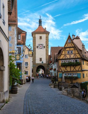 Rothenburg ob der Tauber, Almanya, 25 Ağustos 2024, Ziyaretçiler Rothenburg ob der Tauber 'in pitoresk caddelerinde boş boş geziniyorlar, yarım keresteli evlere ve tarihi saat kulesine hayran kalıyorlar.