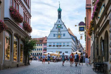 Rothenburg ob der Tauber, 25 Ağustos 2024, ziyaretçiler renkli binalarla çevrili Rothenburg ob der Tauber 'in pitoresk caddelerinde geziniyorlar..