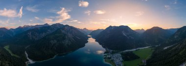 Güneş yükselen dağların ardında batarken Plansee Gölü 'nün sakin suları altın renkleri yansıtıyor. Avusturya' nın kalbine düşünce ve korku salan sakin bir atmosfer yaratıyor..
