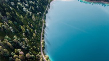 Titrek turkuaz sular, Plansee 'de yoğun yeşilliklerle çevrili kıyı şeridini saran dolambaçlı bir yol gibi berrak gökyüzünü yansıtıyor. Sakin atmosfer keşif ve rahatlamaya davetiye çıkarıyor..
