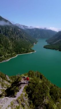 Plansee Avusturya, nefes kesici ve çarpıcı bir manzara. Etrafı canlı yemyeşil bir dağ gölü ile çevrili güzel, sakin bir dağ gölü. Bir dağın tepesinde iki erkek ve bir kadın.