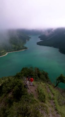 Plansee Avusturya, nefes kesici ve nefes kesici bir hava sahnesi. Bereketli, yeşil dağların arasına kurulmuş sakin bir göl tasvir ediyor. Bir çift adam ve kadın göl manzaralı bir dağ yürüyüşü yapıyorlar.
