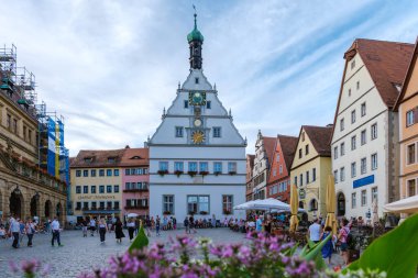 Rothenburg ob der Tauber, Almanya, 25 Ağustos 2024, Ziyaretçiler Rothenburg ob der Tauber meydanında toplandılar, tarihi binalar ve canlı çiçeklerle çevrili.