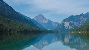 Dağlarda yuva yapmış Plansee Avusturya 'nın sakin suları büyüleyici dağlık manzarayı yansıtıyor ve ziyaretçileri Avusturya' nın vahşi doğasındaki sakin güzelliğin ve açık hava maceralarının tadını çıkarmaya çağırıyor..