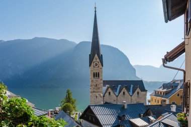 Avusturya 'nın Hallstatt kentindeki büyüleyici köyde, sabah ışığı çan kulesini ve çatıları yıkarken, dingin göl görkemli dağları yansıtarak, huzurlu bir alp atmosferi yaratır..