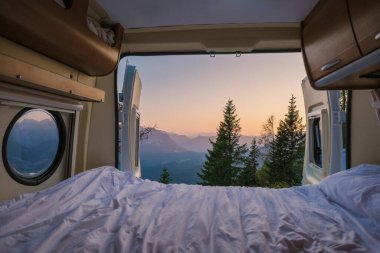 Bir karavana yerleşmiş, rahat bir yatak, Avusturya 'nın sakin dağlarına altın ışığın dökülmesiyle sakin bir sabahı davet ediyor, macera ve keşiflerle dolu bir gün vadediyor. Ezik dağ.