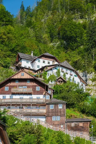 stock image Nestled against a lush green hillside, a cluster of charming wooden houses in Hallstatt showcases traditional Alpine architecture